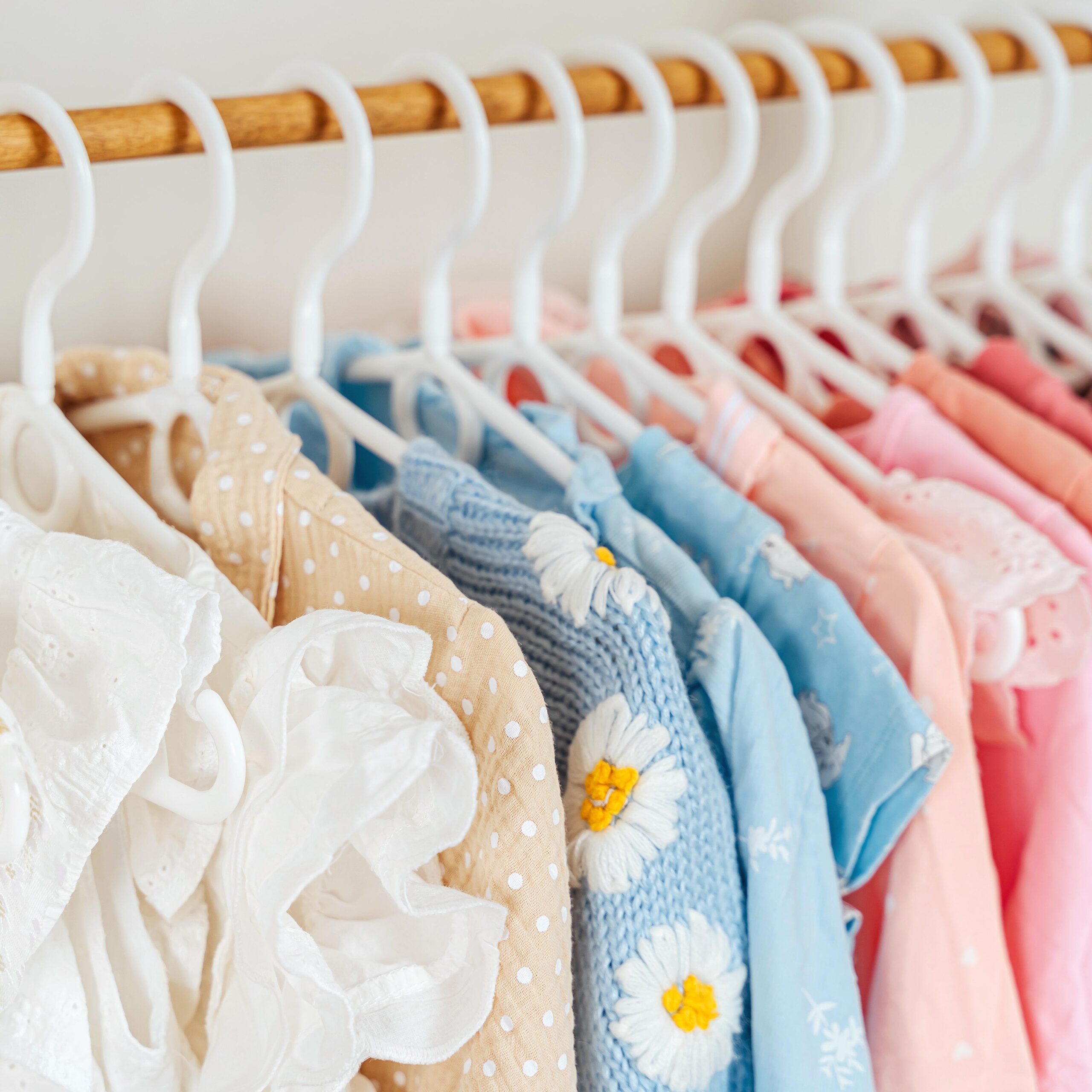 Clothing Rack with children's outfits close up. Home kids wardrobe. Nursery Storage Ideas. Baby Girl Clothes.